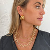 Woman wearing chunky link necklace with chunky yellow gold earrings and necklaces