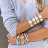 Woman wearing triple strand bracelets in rose, white, and yellow gold plating with white gold plated cut out cuff bracelet