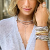 Woman wearing triple strand bracelets with white gold chain necklaces and ring collection