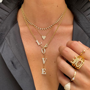 Diamond love lariat on woman's neck layered with shorter yellow gold & diamond necklaces