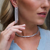 Woman wearing faux linear drop earrings with pave ring and diamond baguette necklace