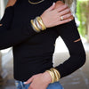 Woman wearing triple strand bracelets in yellow and white gold, with yellow gold herringbone chain necklace