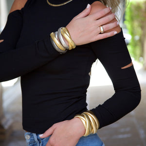 Woman wearing layered statement bracelets with triple strands, in yellow and white gold