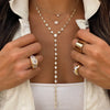 Woman wearing crystal lariat necklace layered under shorter yellow gold chains