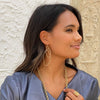Woman wearing organic overlap earrings with yellow gold chunky necklace and cluster ring