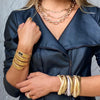 Woman wearing triple strand bracelets in yellow and white gold, with yellow gold chunky chain necklaces