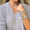 Woman wearing twinkle lariat with layered white gold necklaces and the classic triple strand bracelet