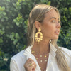 Woman wearing geometric chandelier earrings with yellow gold layered necklaces