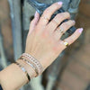 Diamond initial pinky ring displayed on woman's hand with gold and diamond pave bracelets and rings