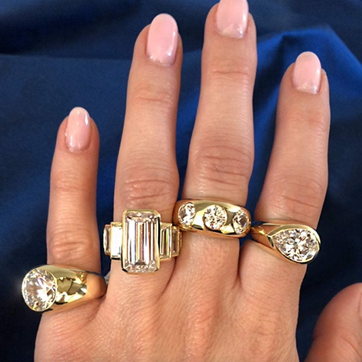 Gypsy ring collection on woman's hand with blue silk background