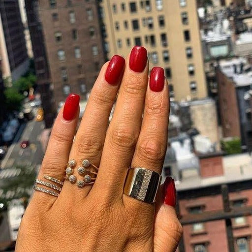 Woman wearing diamond coil ring with thick white gold ring and pave statement ring