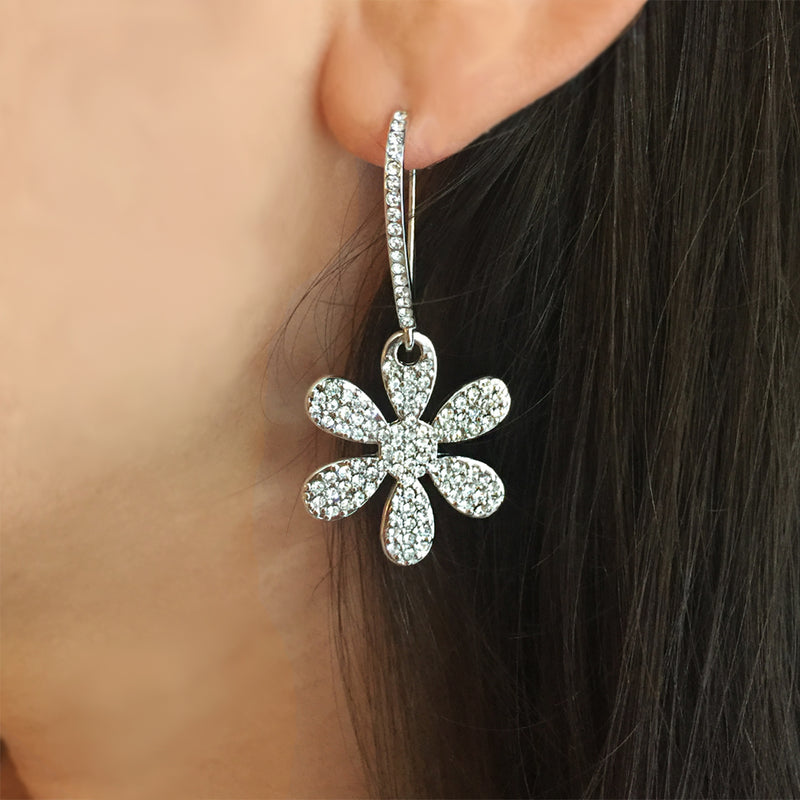 Woman wearing white gold daisy drop earrings