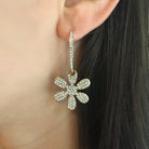 Close up of woman wearing yellow gold daisy drop earrings