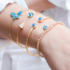 Evil eye charm bracelet on wrist styled with other yellow gold and turquoise evil eye bracelets
