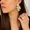 Woman wearing diamond emerald cut ring paired with pave flower petal statement drop earrings