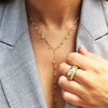 Woman wearing triple stone ring with yellow gold lariat necklace