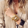 Woman wearing twist snake bracelet with classic triple strand bracelet and emerald ring