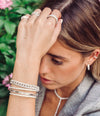 Woman wearing pave tennis bracelet with white gold pave bracelets and rings